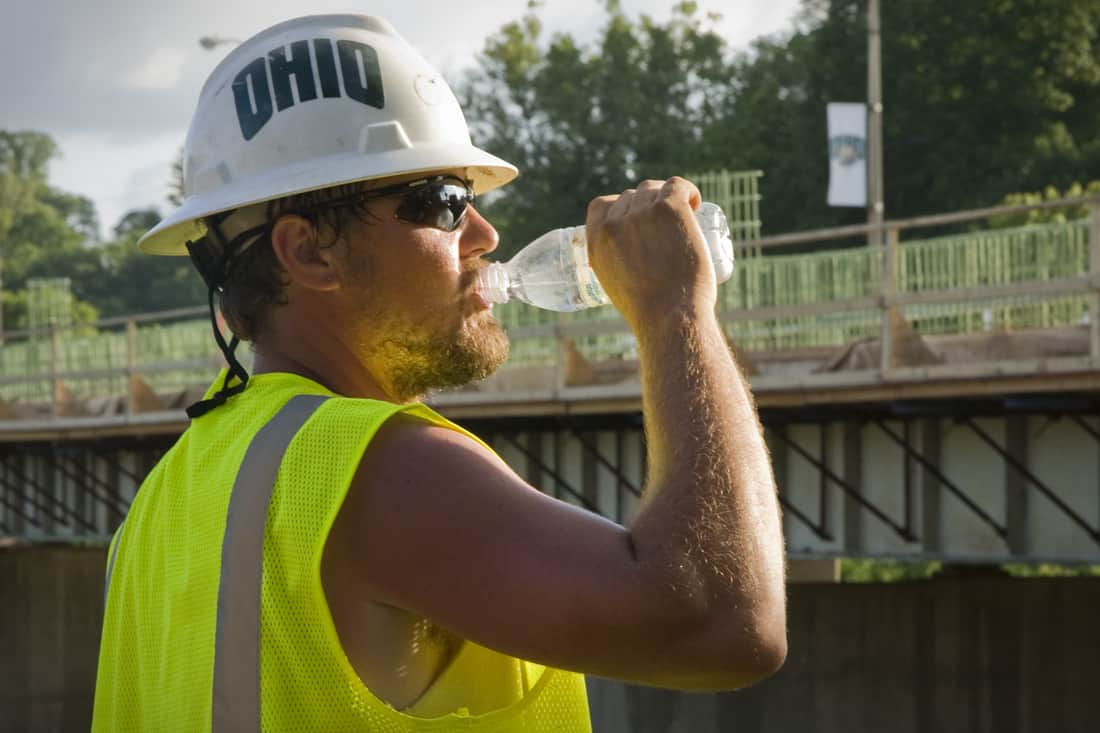 a construction worker drinks out of a water bottle