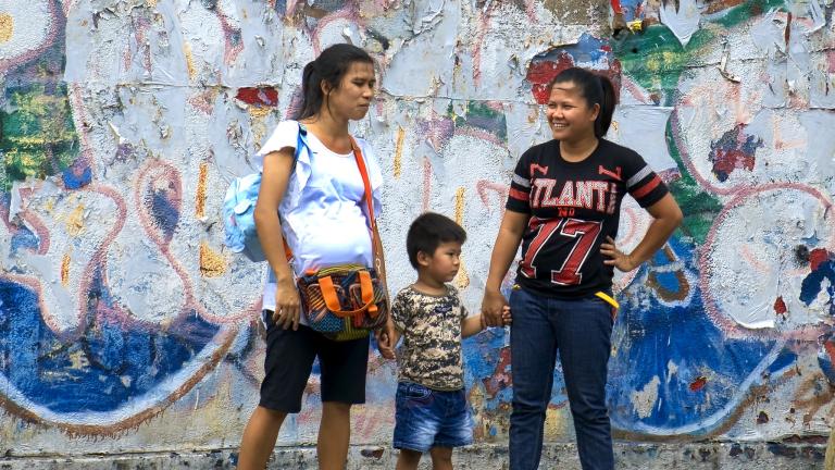 Two women and a child standing at a bus stop