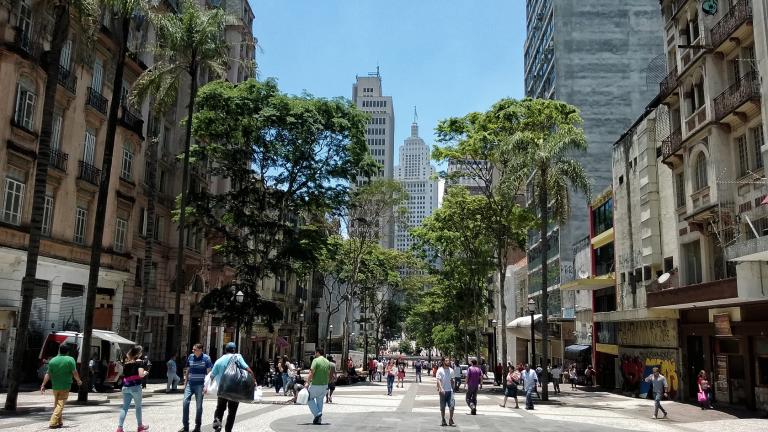 People walking down an urban street lined with trees.