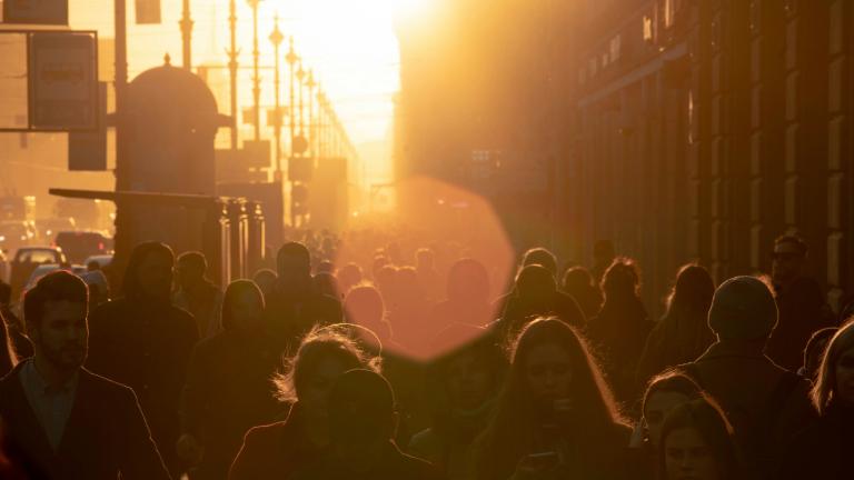 people walking down a city street into the sun