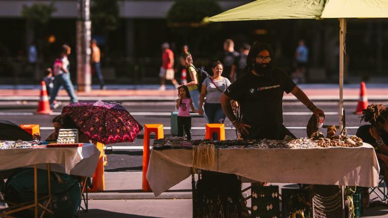 a street vendor stands under an umbrella for shade